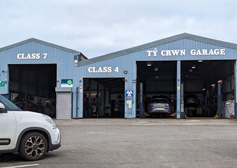 The front of Ty Crwn Garage. It's pale blue, with white writing above each door, saying 